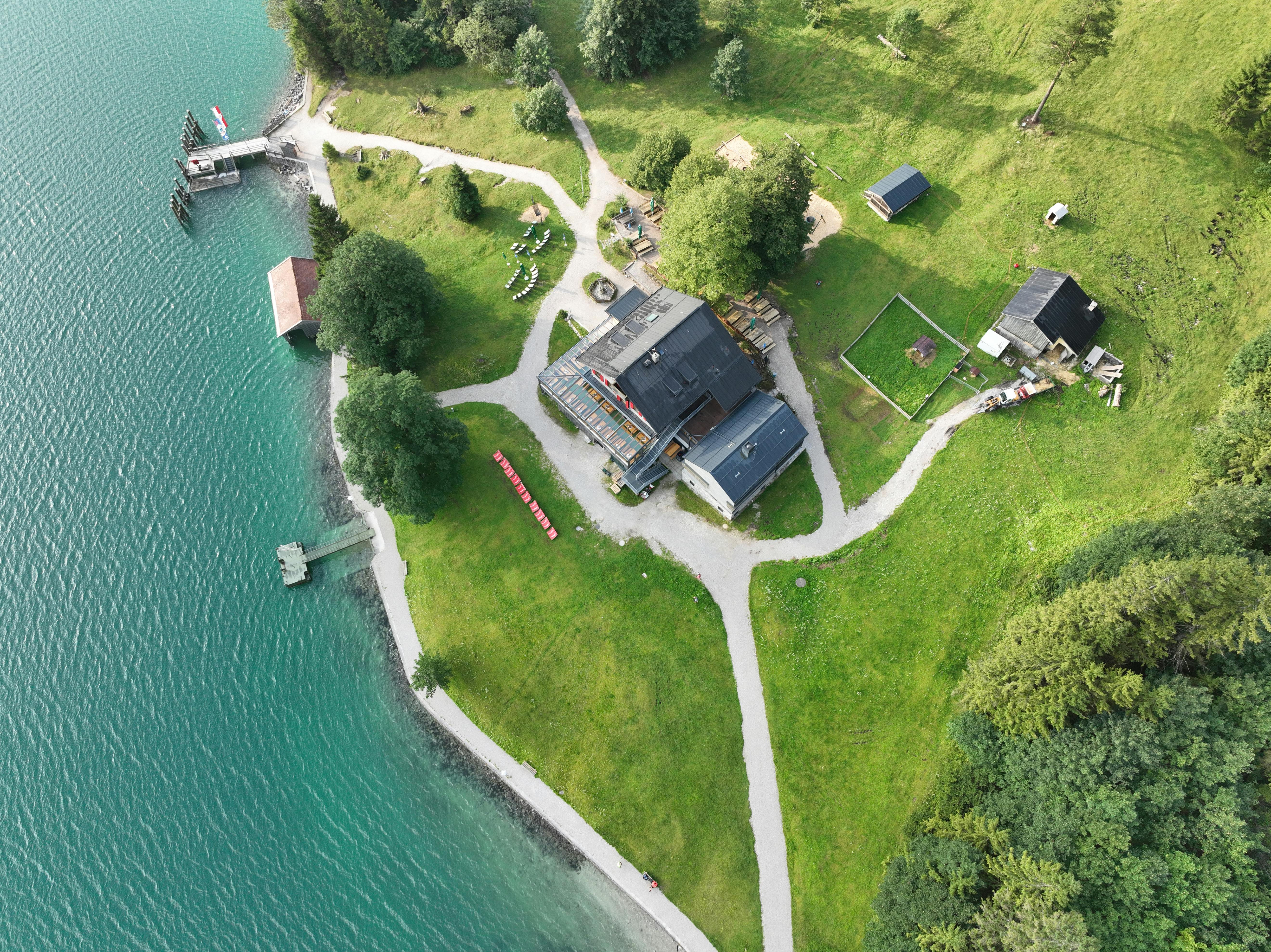 Stunning aerial view of a waterfront lodge by a lake with surrounding greenery and dock.