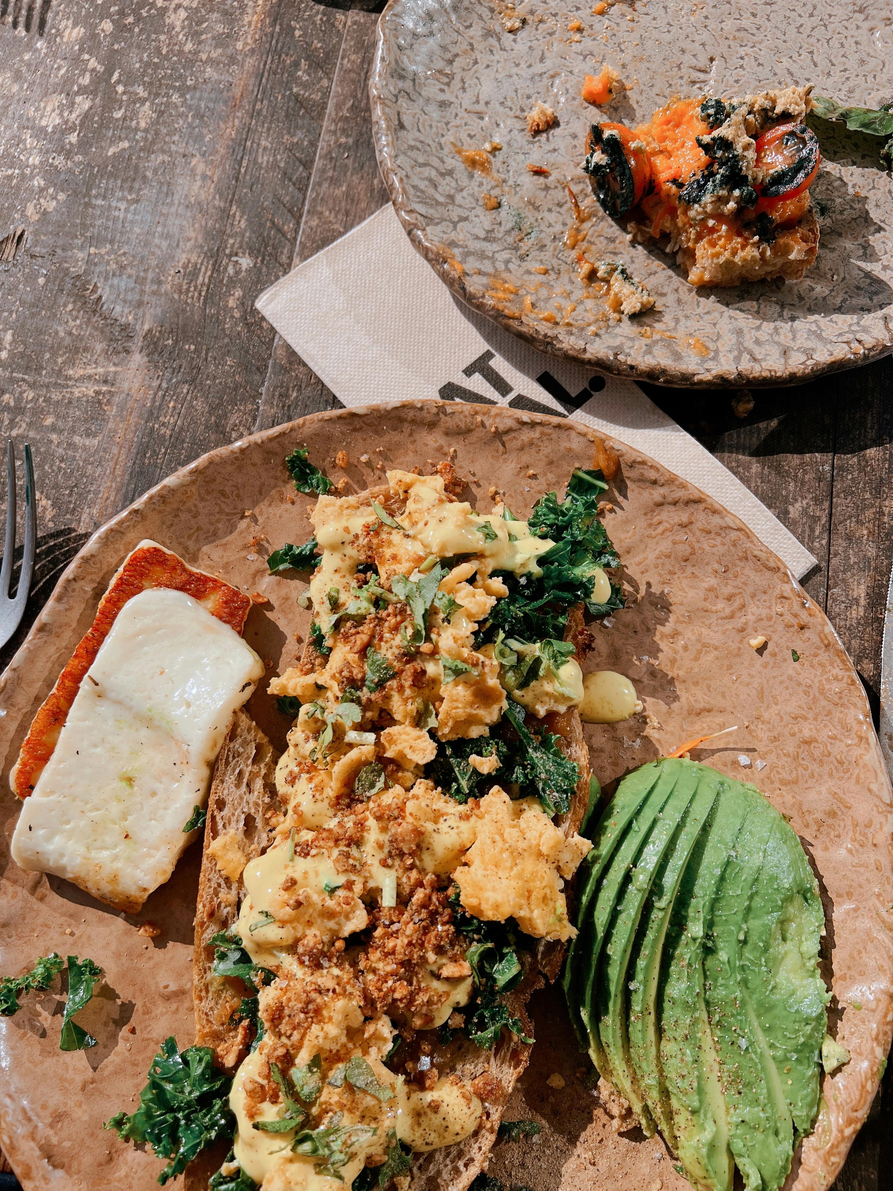Delicious brunch with avocado, kale, and more on rustic plates. Perfect for healthy lifestyle inspiration.