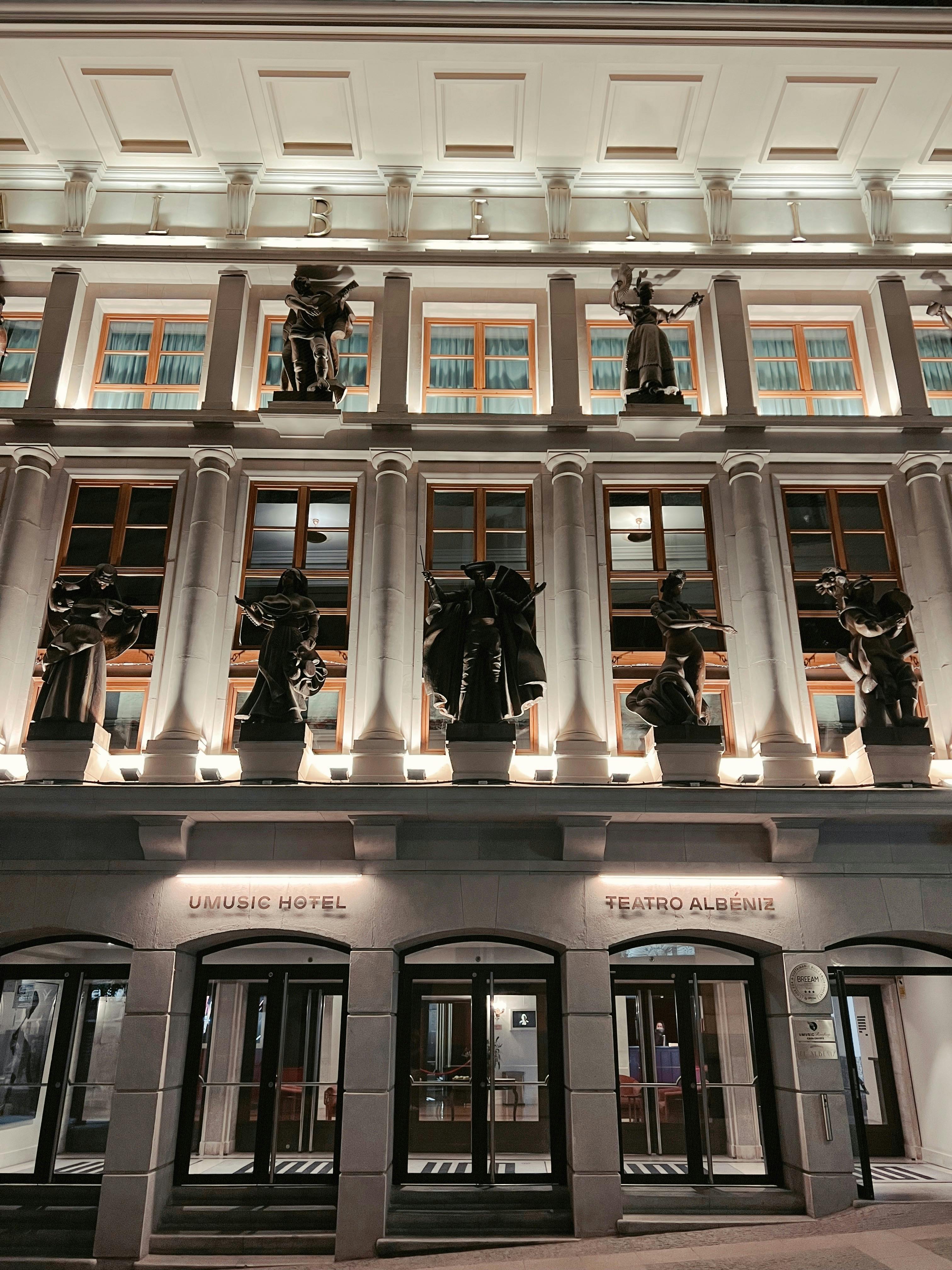 Ücretsiz Teatro Albéniz'in aydınlatılmış cephesinde gece aydınlatması altında klasik heykeller yer alıyor. Stok Fotoğraflar