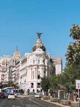 Beautiful view of Metropolis Building in Madrid with clear blue sky and street scene.