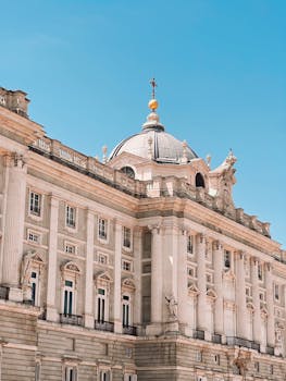 The Royal Palace of Madrid showcases its classic architecture under a bright blue sky.