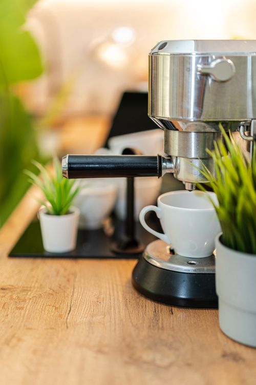 Free Stylish espresso machine in a cozy kitchen with potted plants and a coffee cup ready to brew. Stock Photo