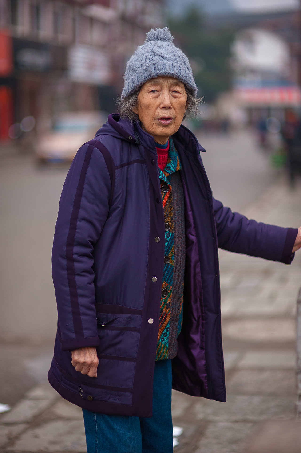 Senior woman in a knit pom hat and purple winter coat