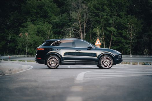 Stylish black SUV parked on a quiet road by a dense forest.