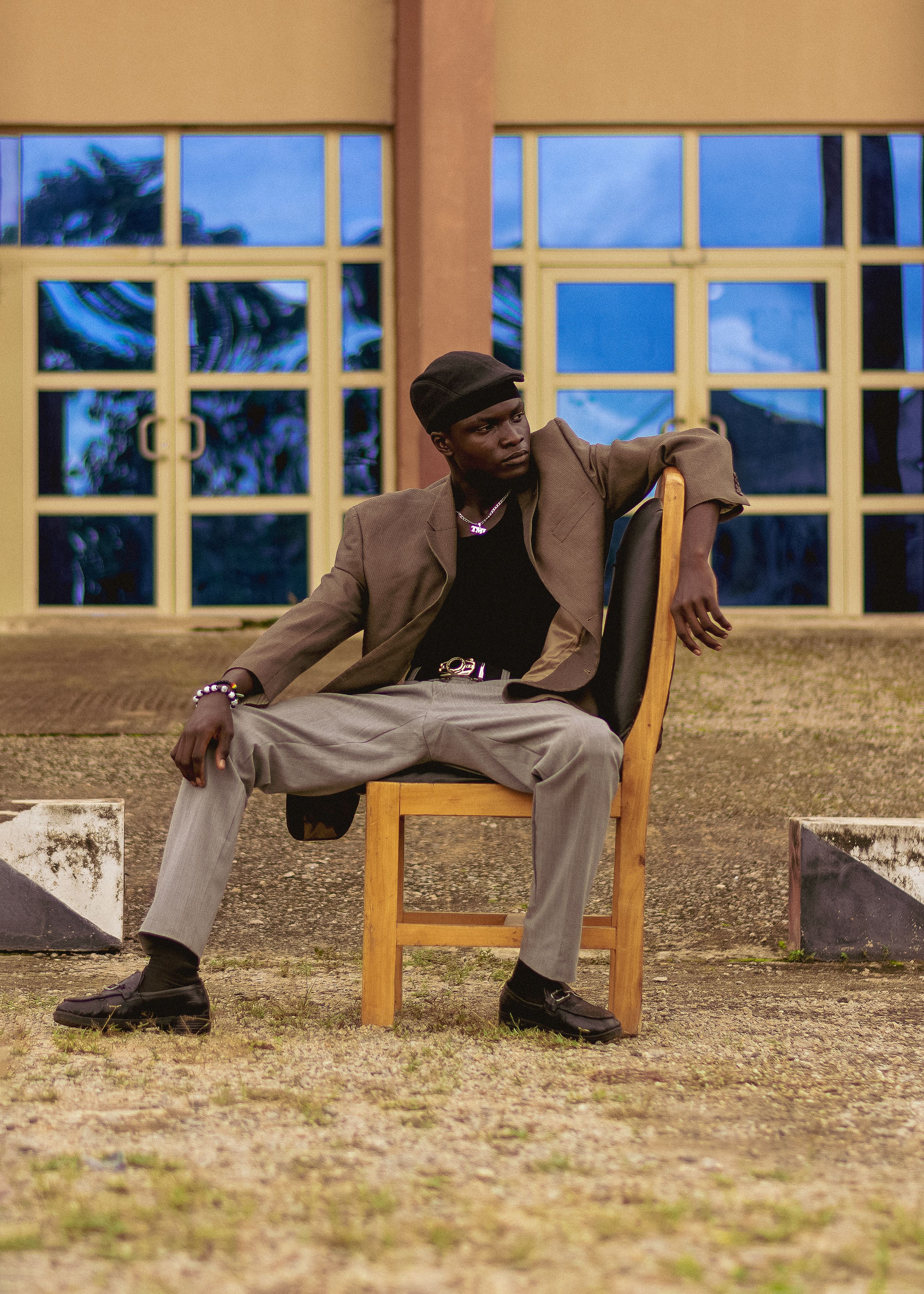 Fashion-forward individual sitting stylishly outside a modern building.