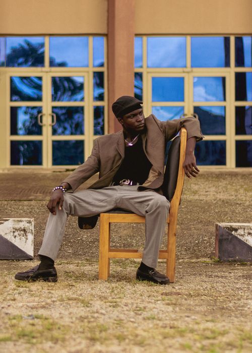 Free Fashion-forward individual sitting stylishly outside a modern building. Stock Photo