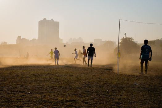 Vibrant scene of boys playing football on a dusty field in Kolkata, capturing youthful energy.