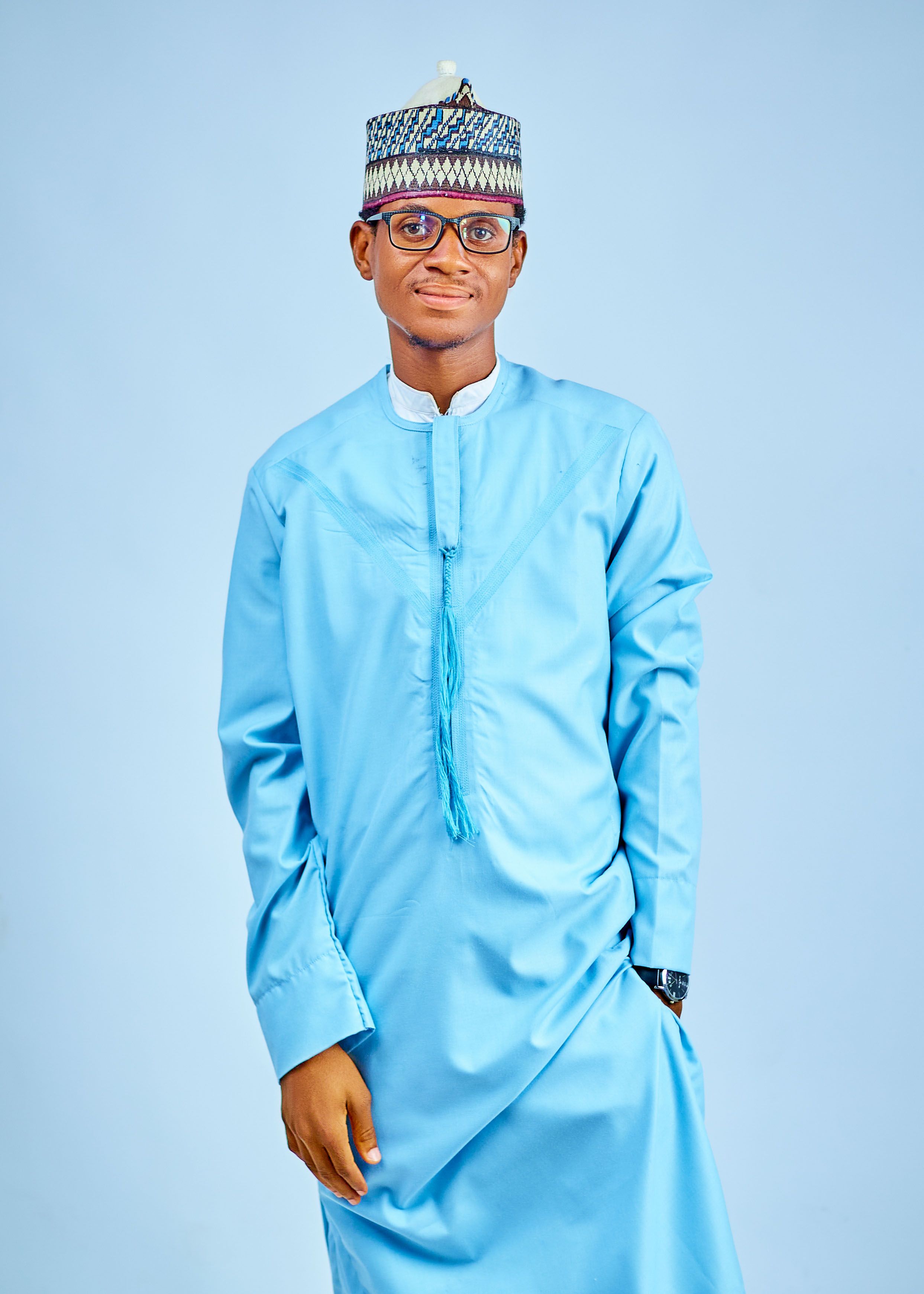 Portrait of a young man wearing a traditional blue outfit and hat, posing confidently.