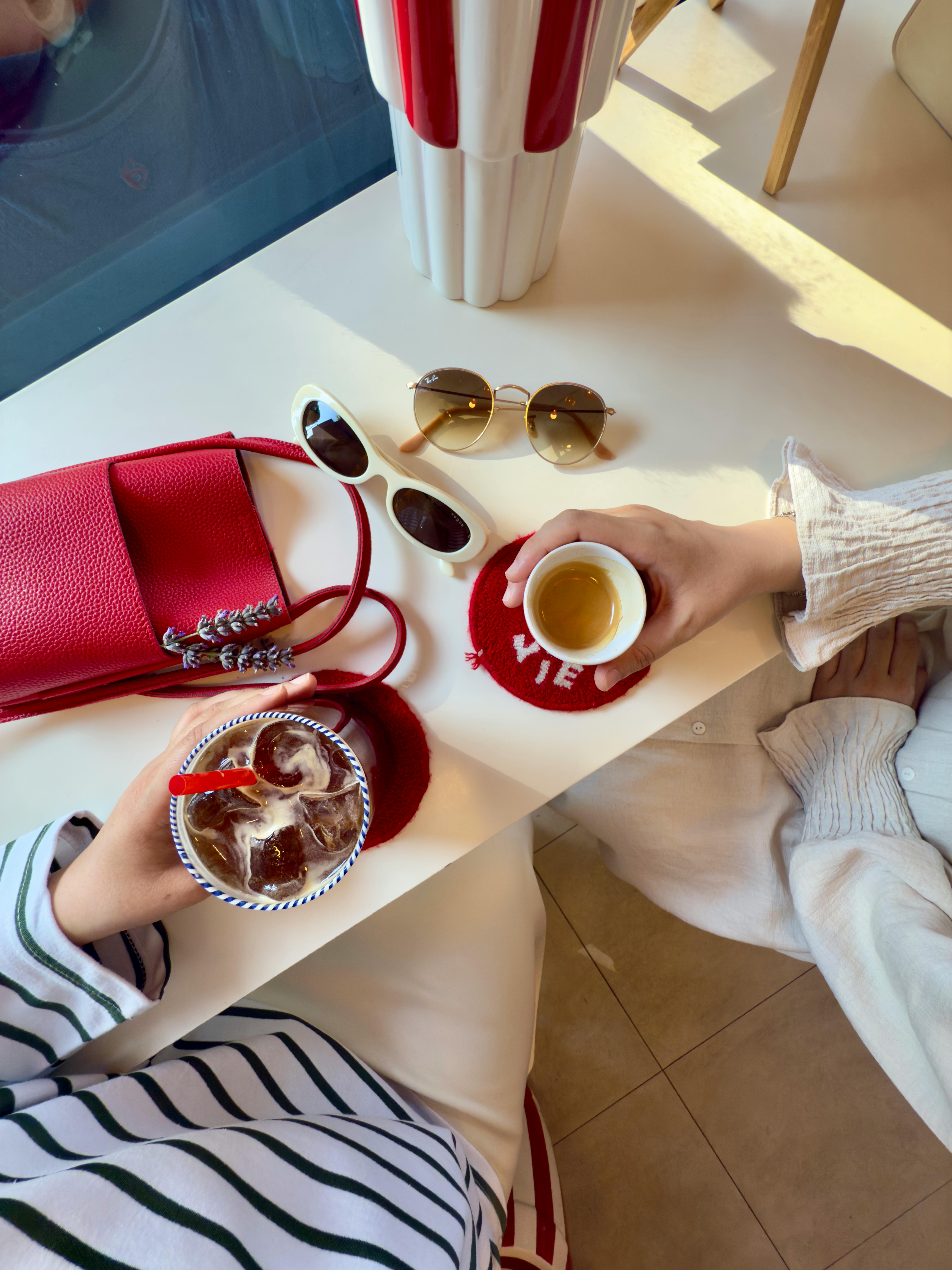 Overhead view of a stylish coffee date with accessories and two people enjoying beverages.