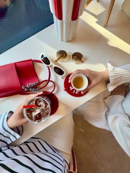 Overhead view of a stylish coffee date with accessories and two people enjoying beverages.