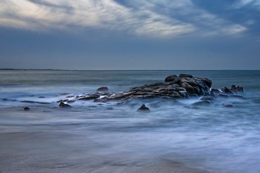 Capture of a tranquil rocky seashore under a moody sky in Bretagne, France.