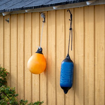 Hanging orange and blue buoys on a yellow wooden wall in Skanör-Falsterbo, Sweden.
