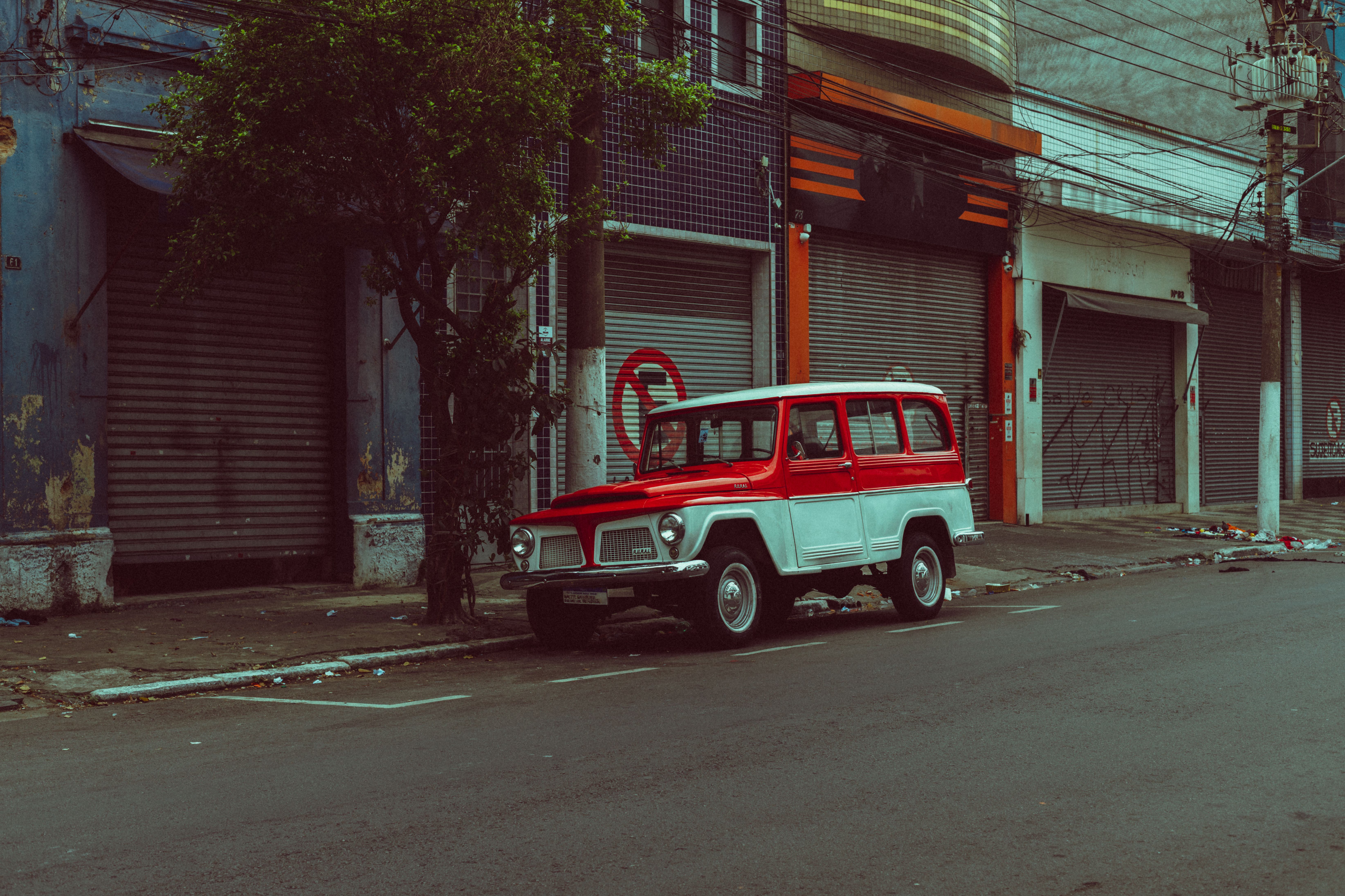 Classic red and white vintage jeep parked on an empty street with closed shops.