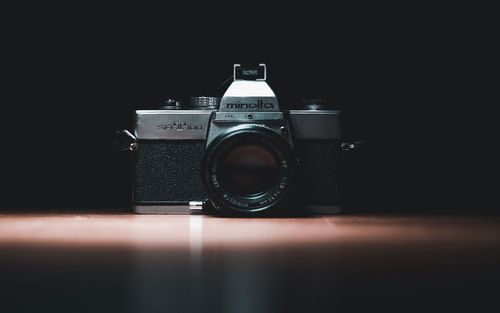 Free Classic Minolta SR-T 100 film camera with lens in dark moody setting, showcasing retro photography equipment. Stock Photo