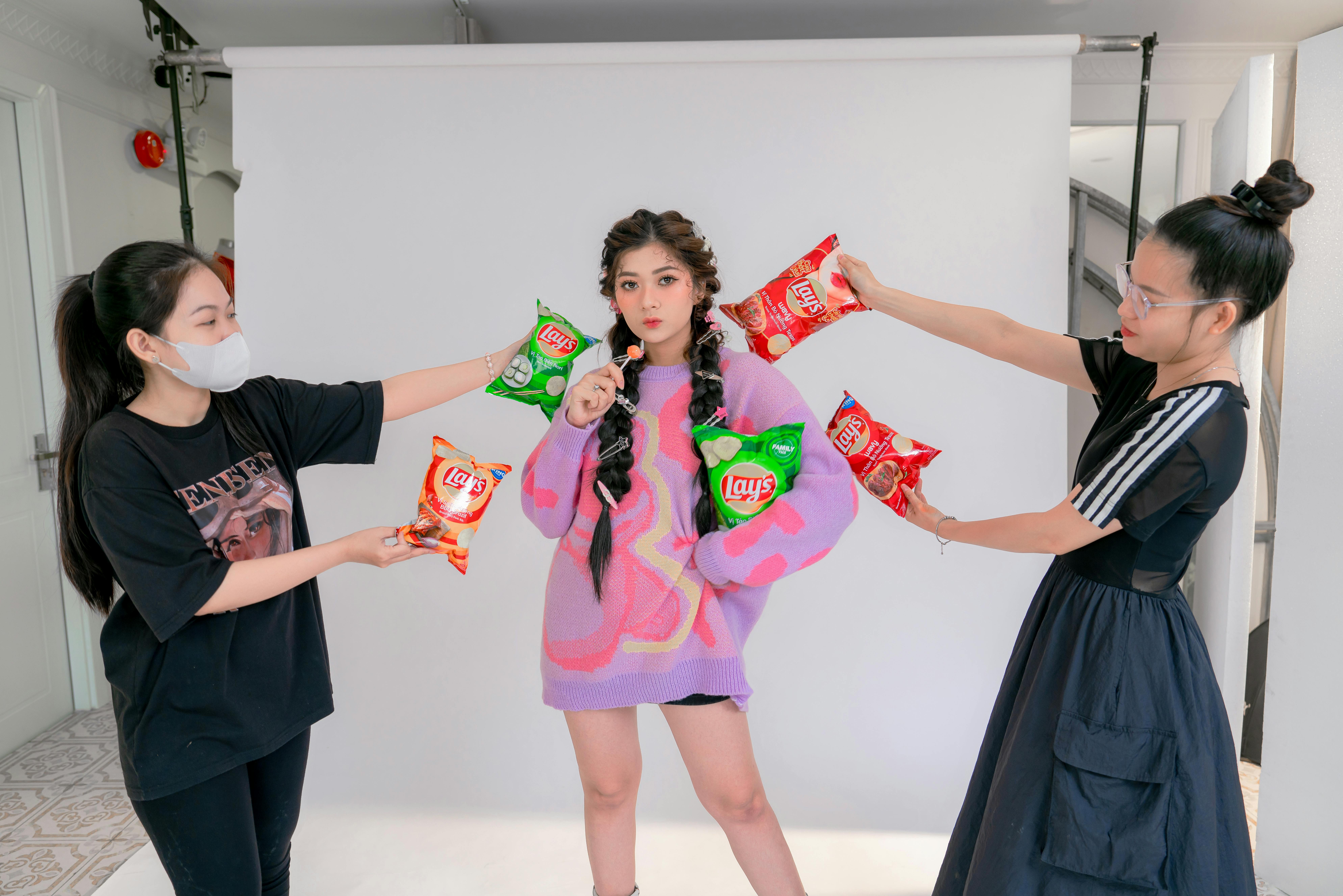 Three young women showcasing Lay's chips in a vibrant studio setup.
