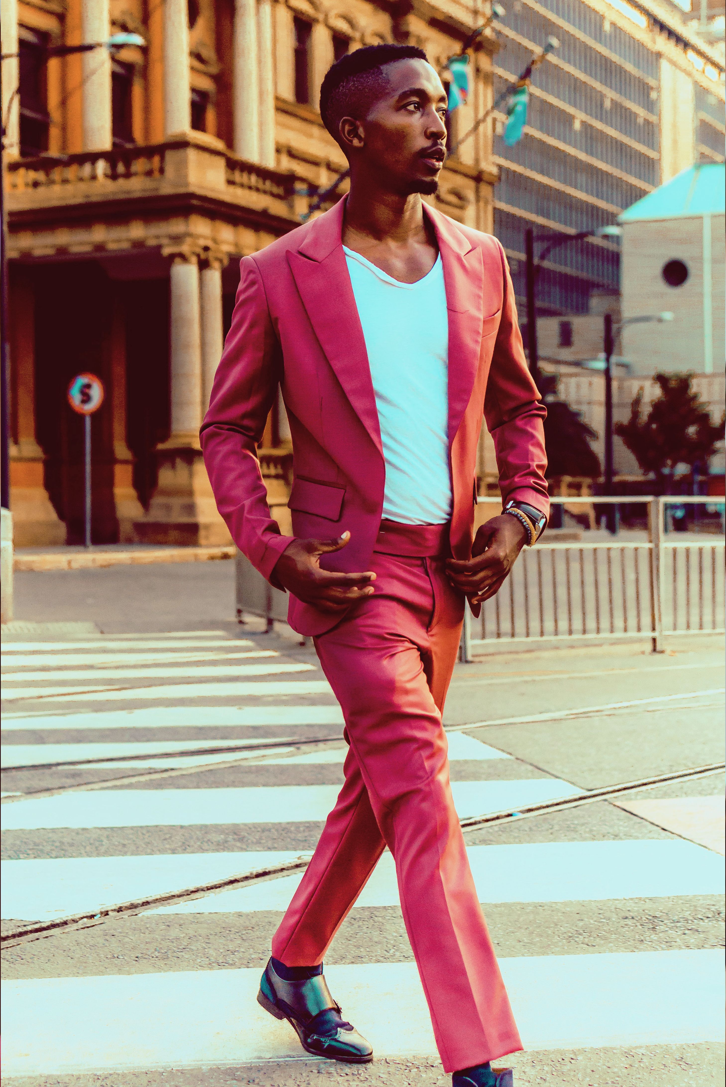 Confident man in a pink suit walking on a crosswalk in downtown Pretoria, South Africa.