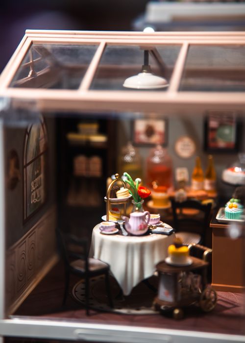 Free Charming miniature indoor café scene featuring an afternoon tea setup with pastries and kettle. Stock Photo
