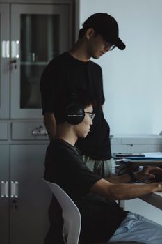 Two young men collaborating on a computer project in a modern office setting, focused and engaged.