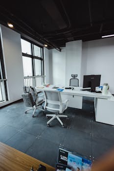 Sleek and minimalist office workspace featuring modern furniture and a large window view.
