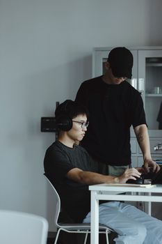 Two adults collaborating in a modern office, one wearing headphones.