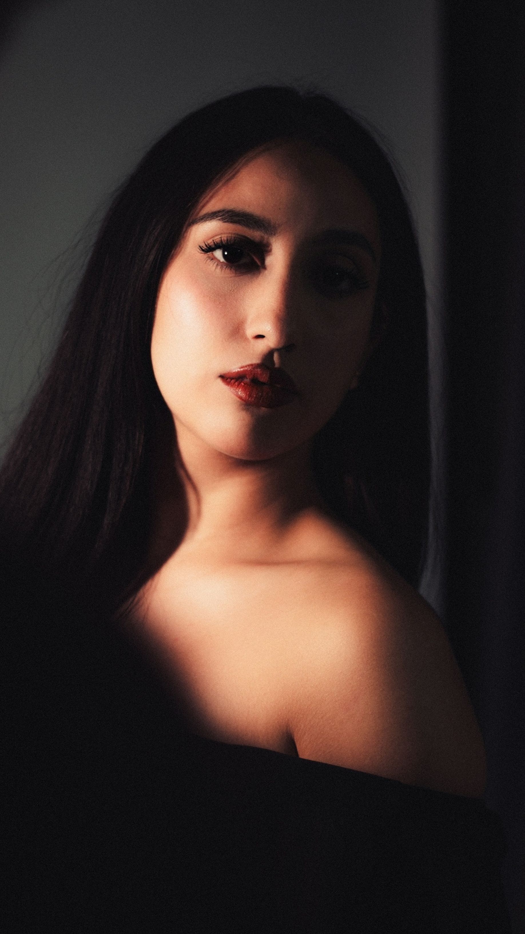 A striking portrait of a woman with dark hair, showcasing dramatic lighting and a serene expression.. pexels, striking, portr