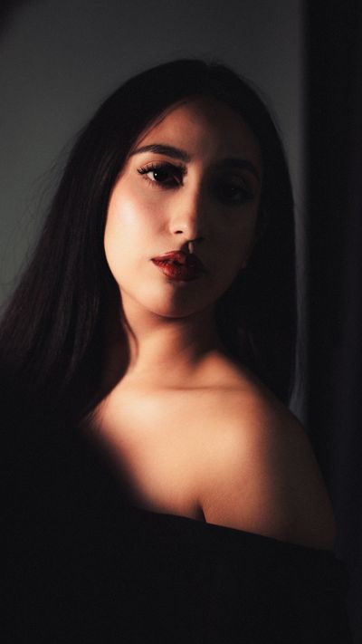 A striking portrait of a woman with dark hair, showcasing dramatic lighting and a serene expression.