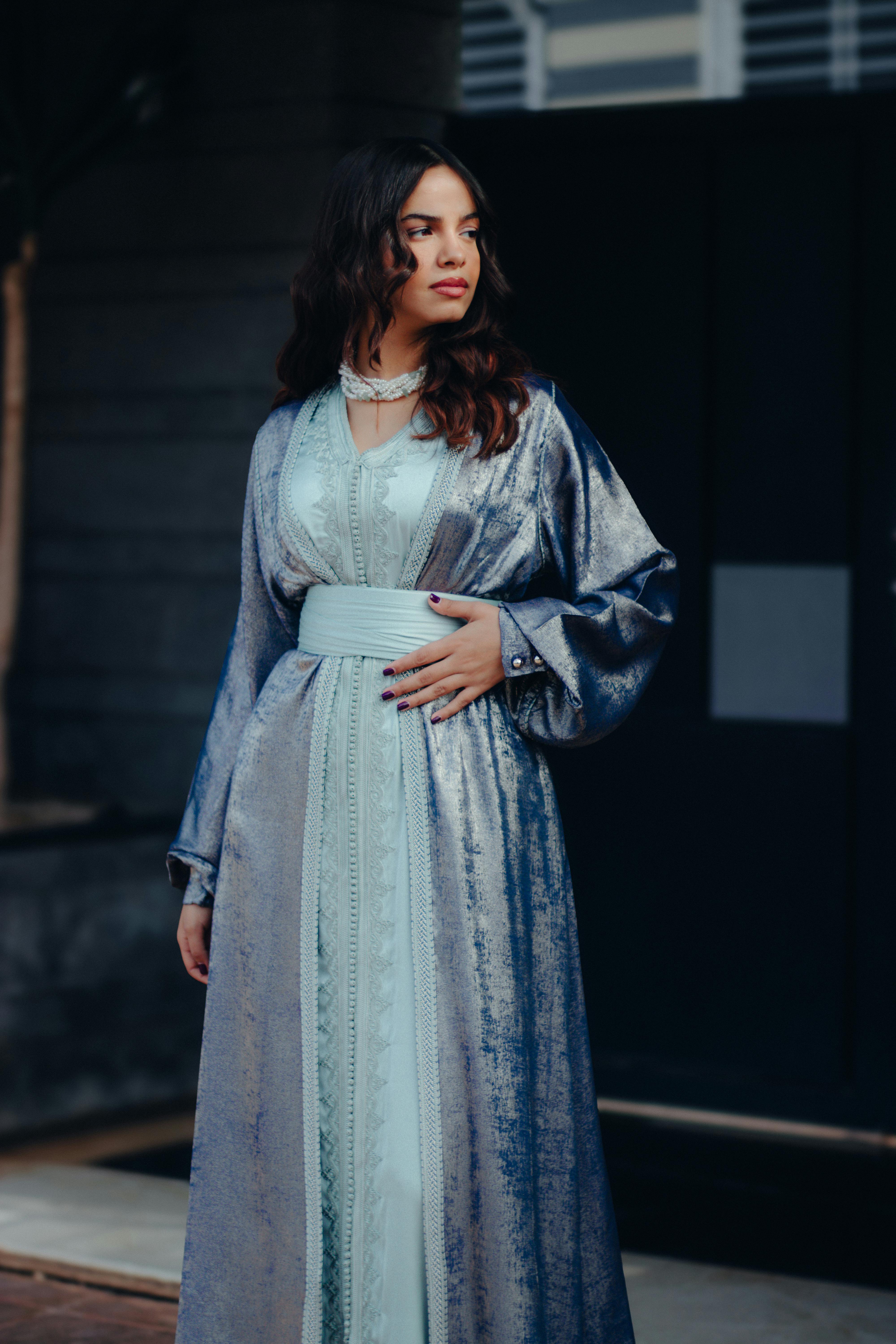 Free A woman in a stylish blue satin dress poses gracefully outdoors, showcasing elegance. Stock Photo