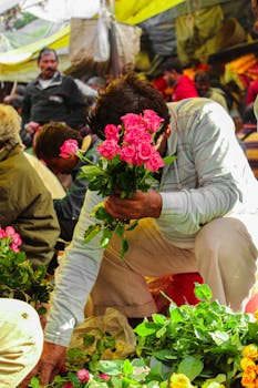 Man arranging roses in a lively outdoor flower market.