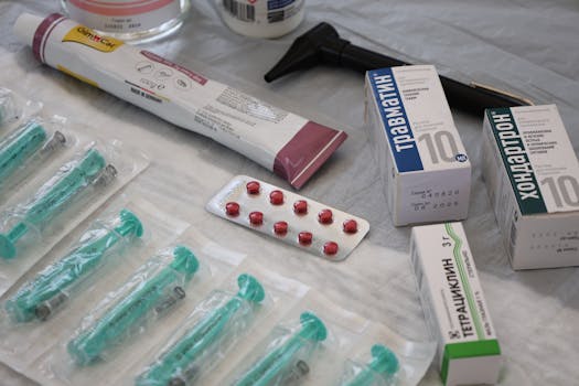 Flat lay of medical supplies including syringes, pharmaceuticals, and an otoscope on a table.