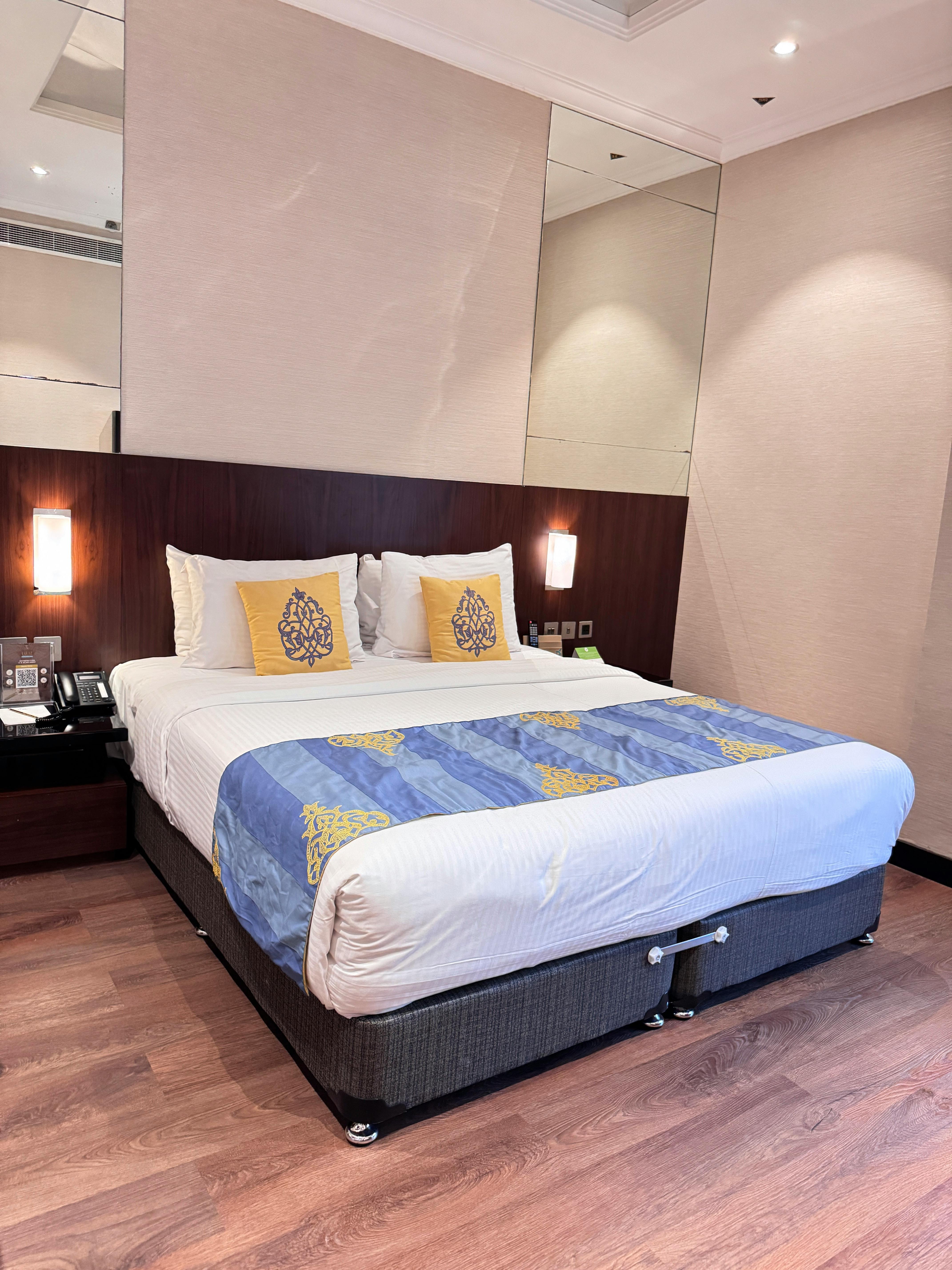 Elegant hotel room with large bed, modern decor, and soft lighting.