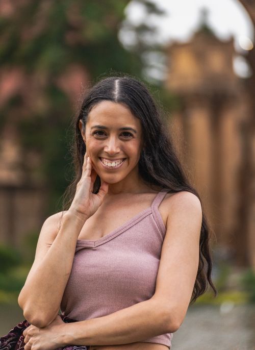 Free A cheerful young woman poses with a smile, wearing casual summer clothing outdoors. Stock Photo