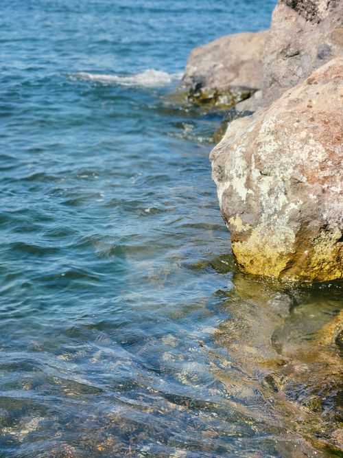 Free Serene rocky shoreline with clear blue water, perfect for tranquility and nature themes. Stock Photo