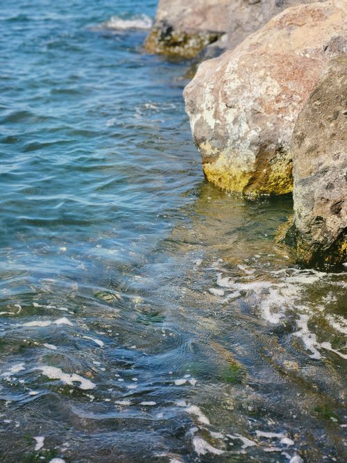Free Serene image of clear water lapping against sunlit rocks. Stock Photo