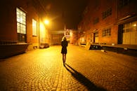 女人走在一条有照明的城市小巷里，独自一人，投下戏剧性的阴影