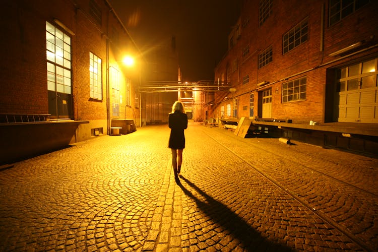 Back View Of A Woman Walking On Street At Night