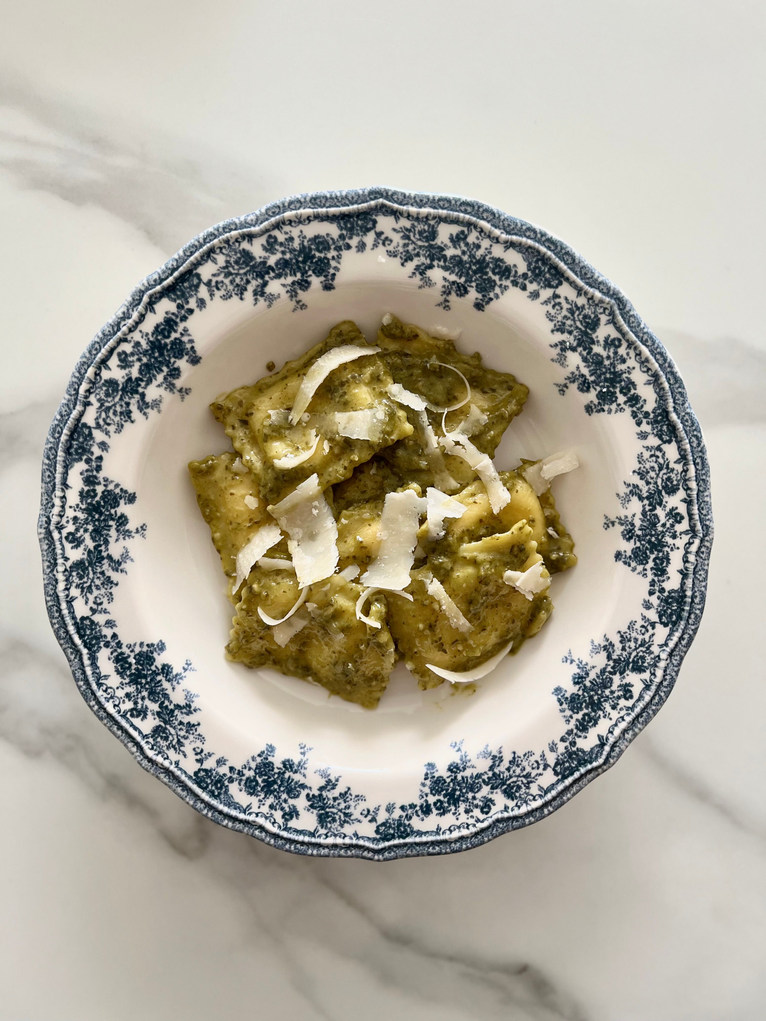 Bowl of agnolotti pasta with blue and white decorative dish showing filling detail