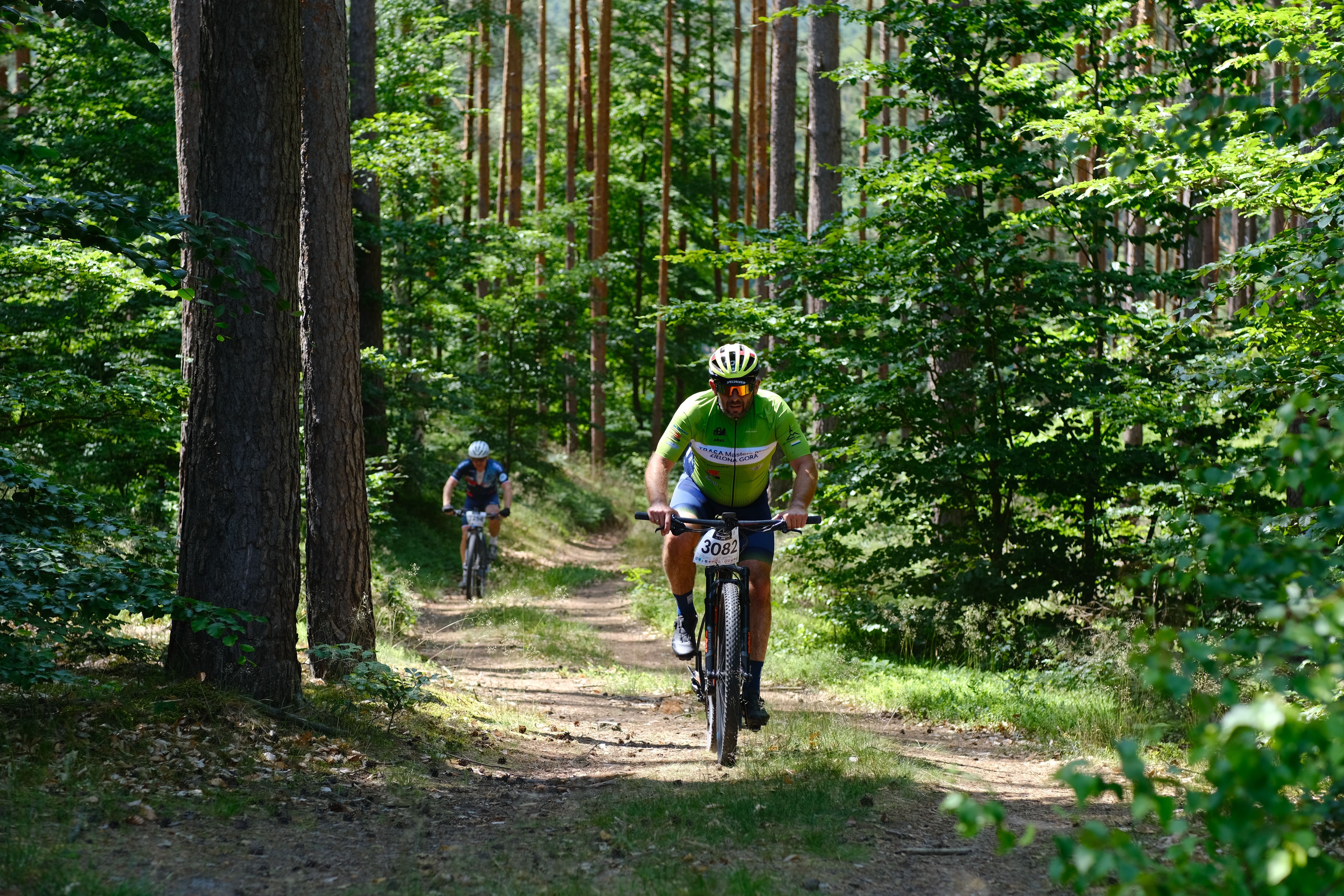 Two bikers on a forest trail enjoying a competitive mountain bike race.