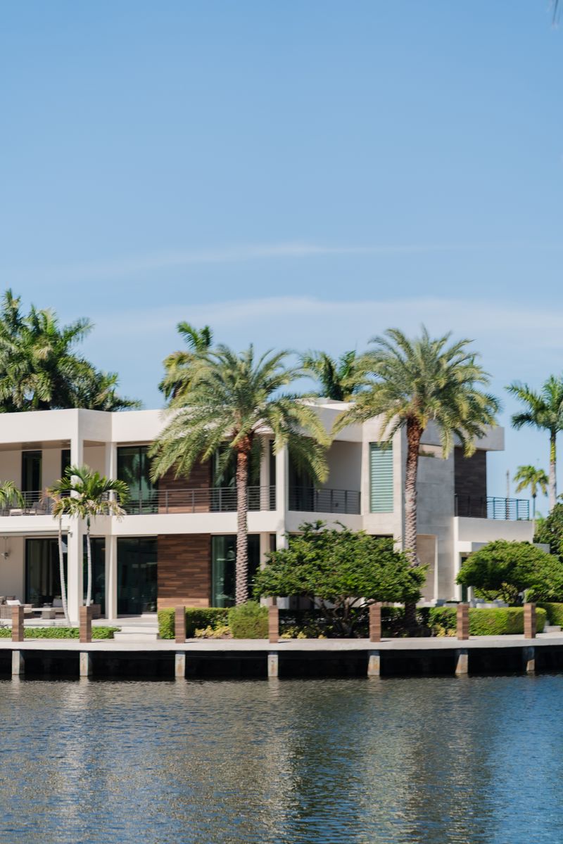 Modern waterfront villa surrounded by palm trees under a blue sky