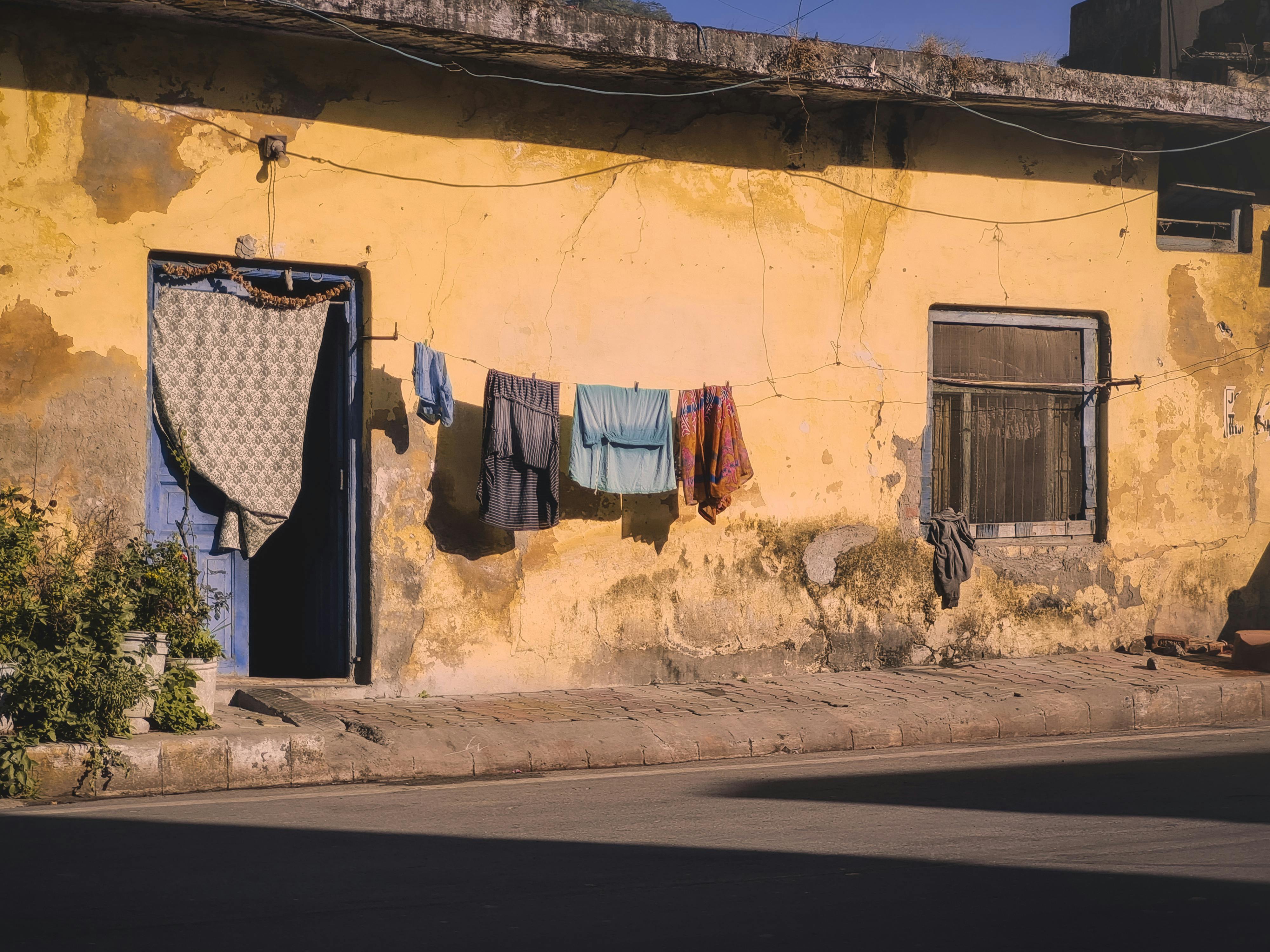 Rustic yellow wall with laundry drying, casting shadows in warm daylight.