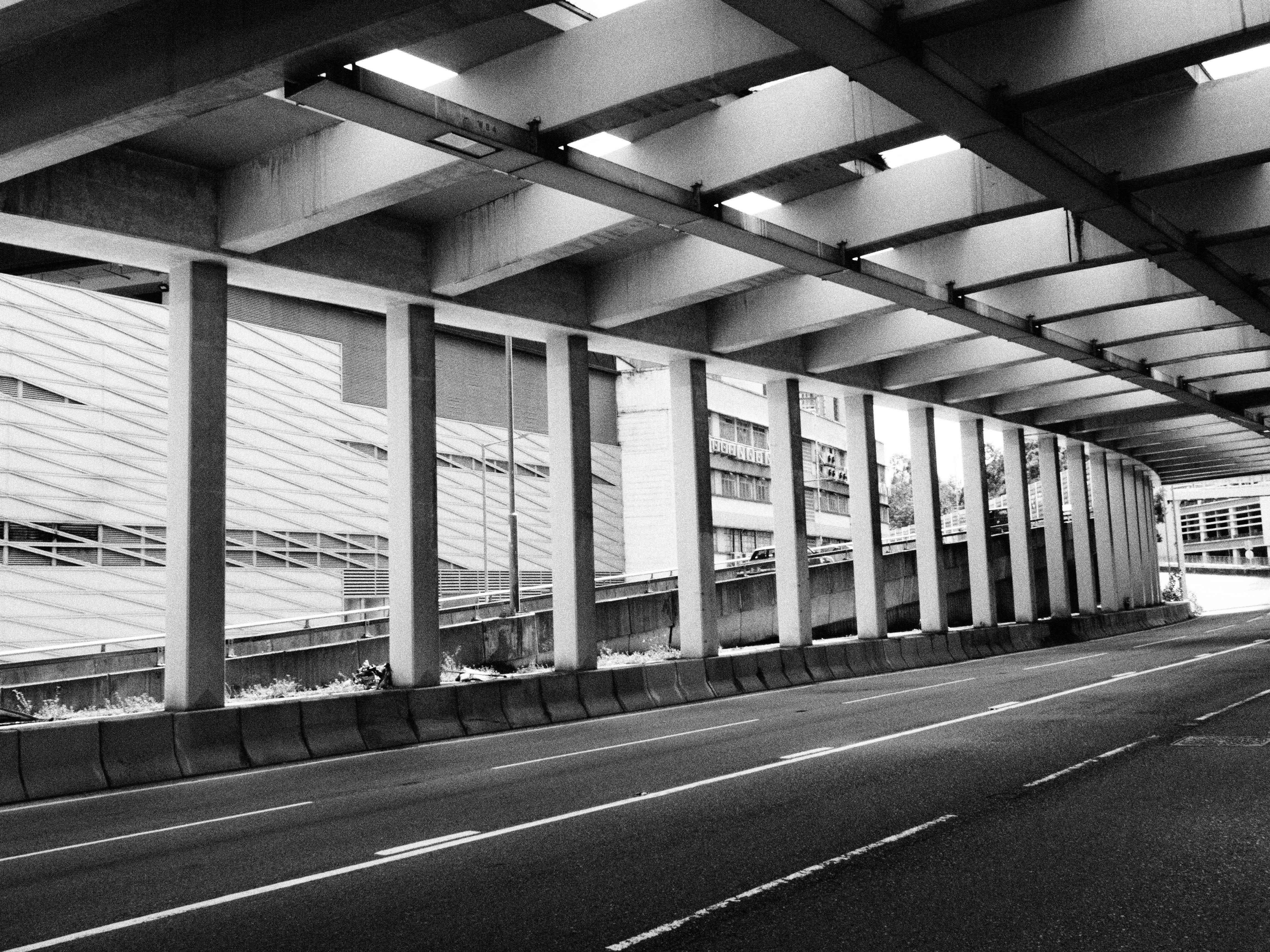 A striking black and white photo of an urban underpass, showcasing the architecture of Hong Kong.