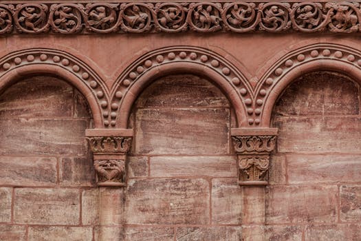 Close-up of decorative red brick arches with intricate carvings in a historic building facade.