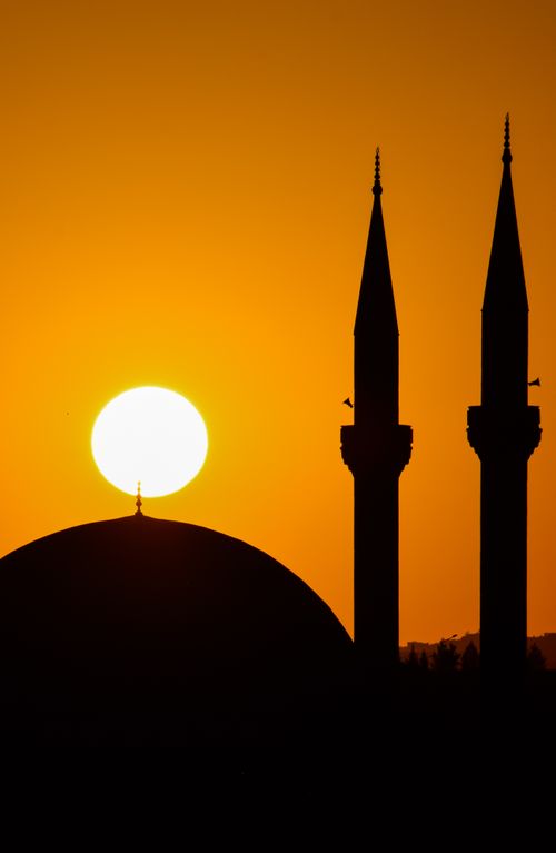 Free A stunning silhouette of mosque minarets against a vibrant sunset in Siirt, Türkiye. Stock Photo