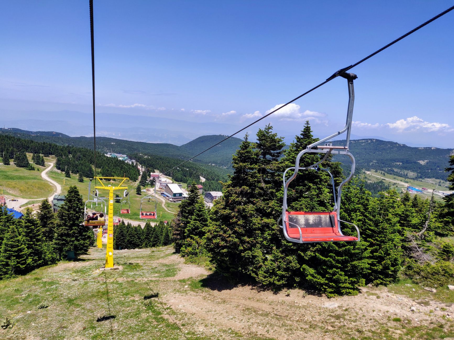A picturesque view of a chairlift amidst the lush greenery of Uludağ, Turkey under clear blue skies.