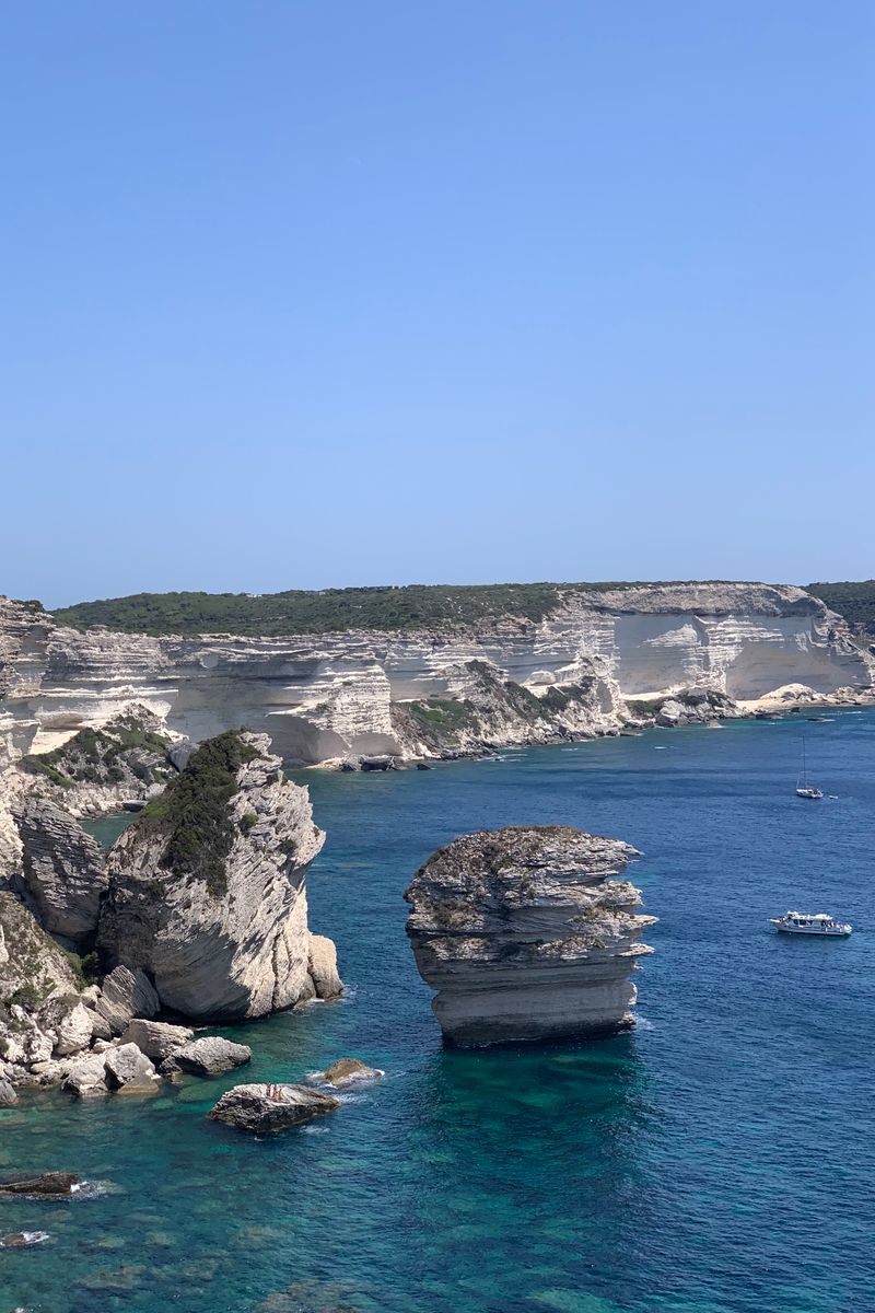 Breathtaking view of towering cliffs and clear blue waters in Bonifacio, Corse, France with boats.