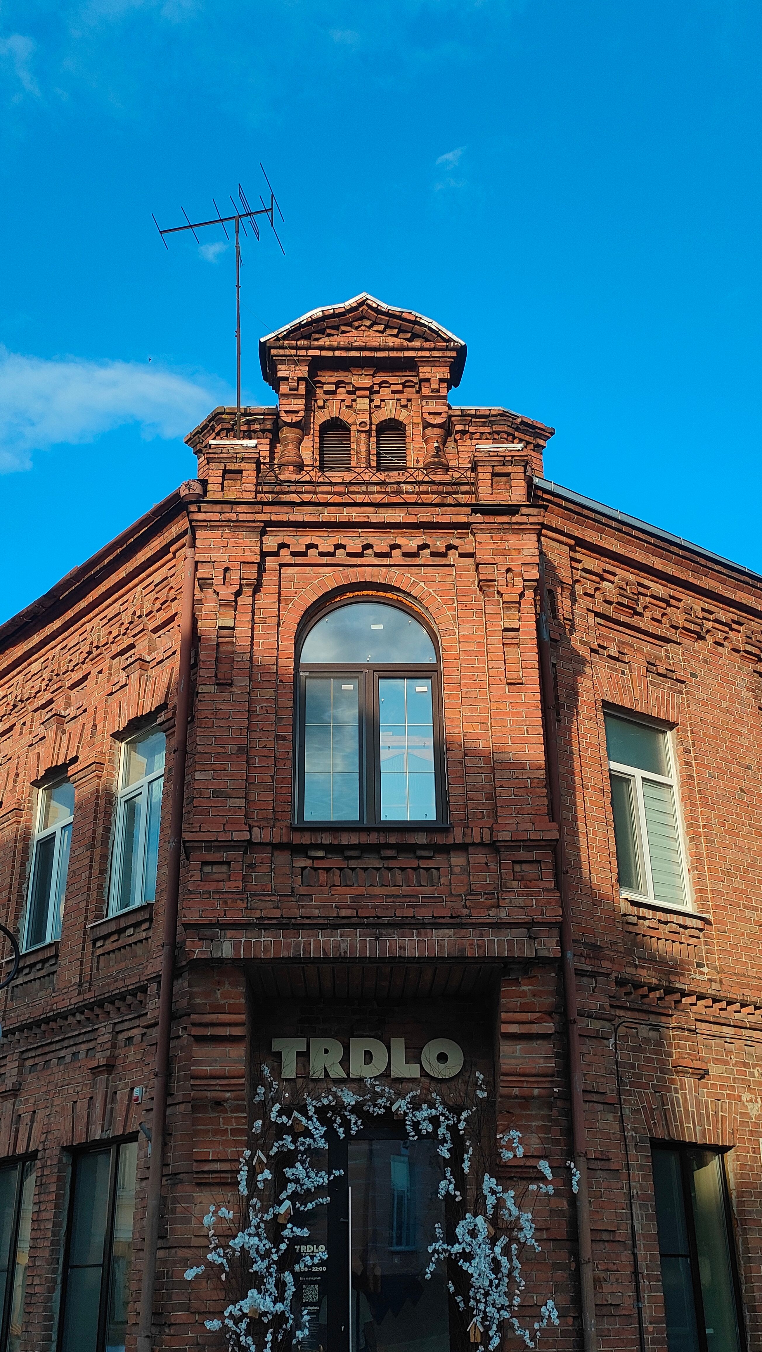 Vintage brick building facade with intricate details against a clear blue sky.