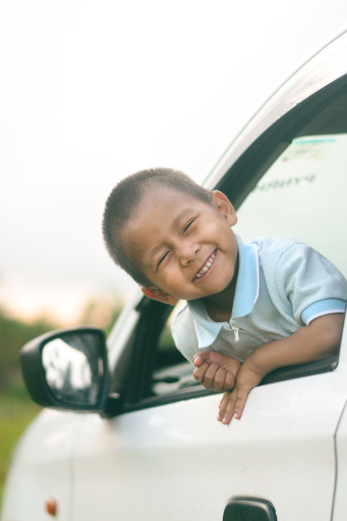A smiling boy leaning out of a car window