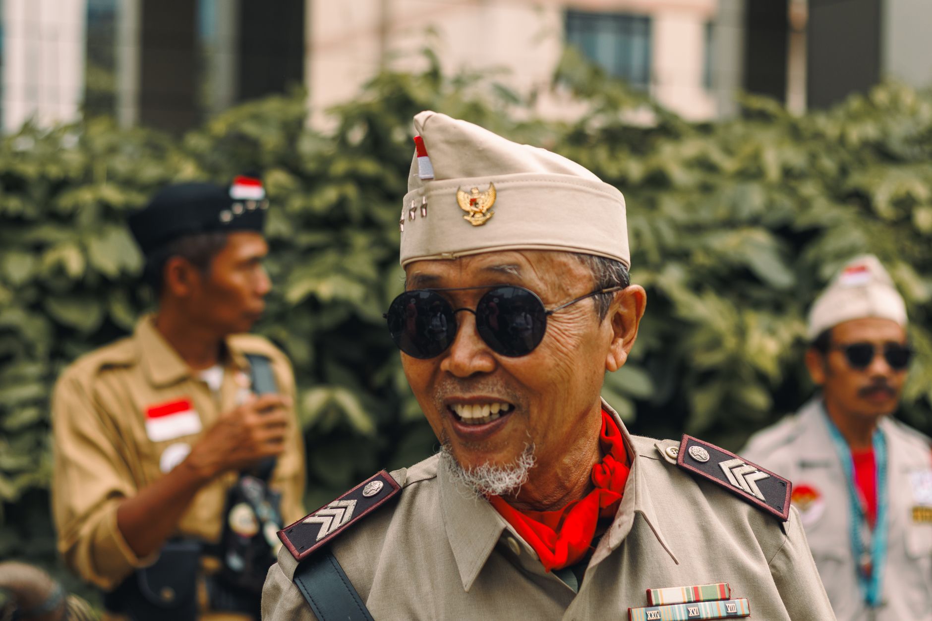 Elderly man in vintage military outfit smiling outdoors, capturing a moment of historical reenactment.