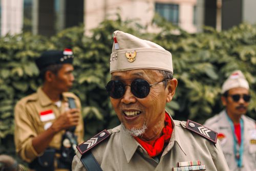 Free Elderly man in vintage military outfit smiling outdoors, capturing a moment of historical reenactment. Stock Photo