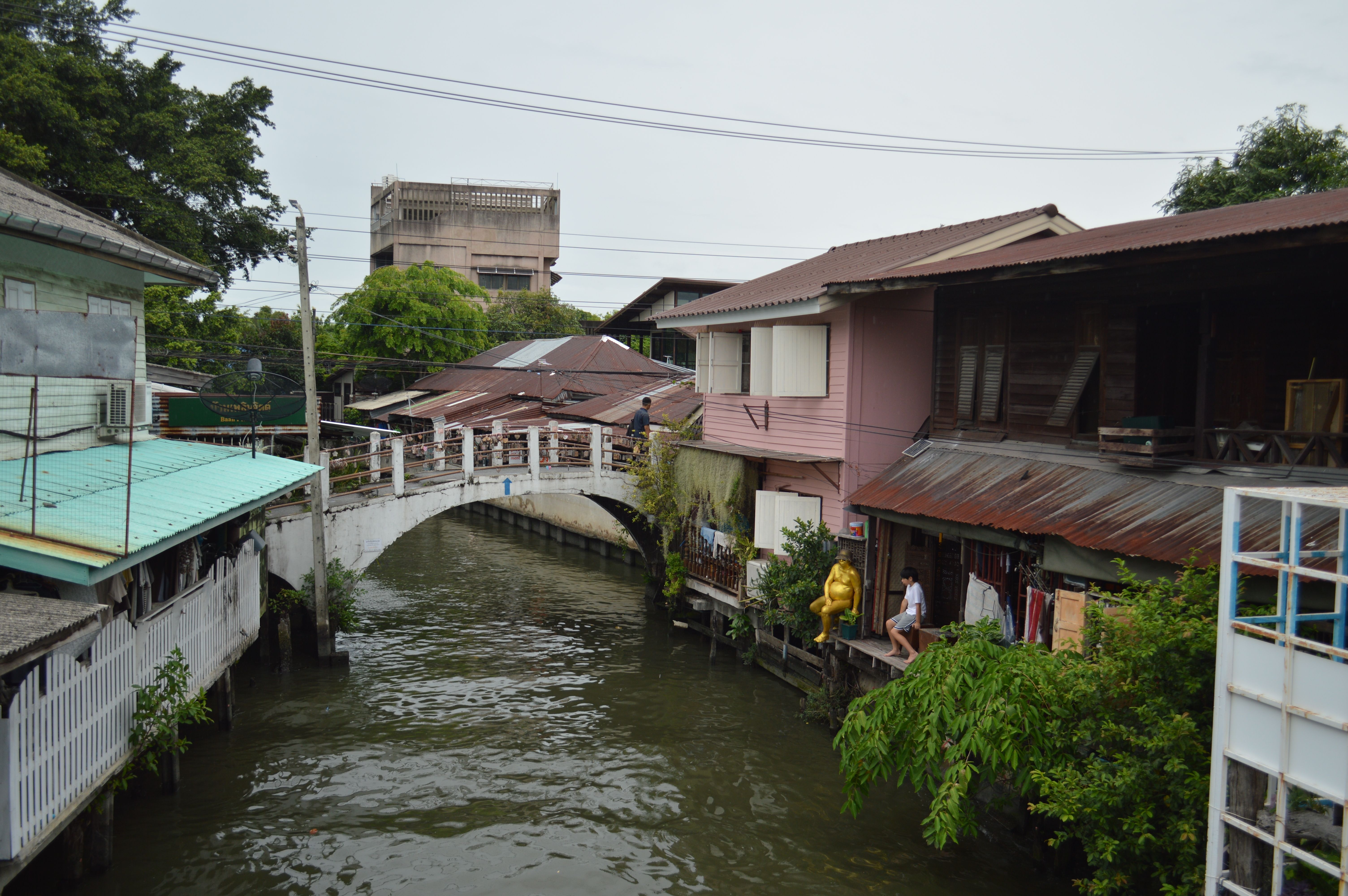 Serene canal scene with a bridge and traditional riverside houses in a Thai town