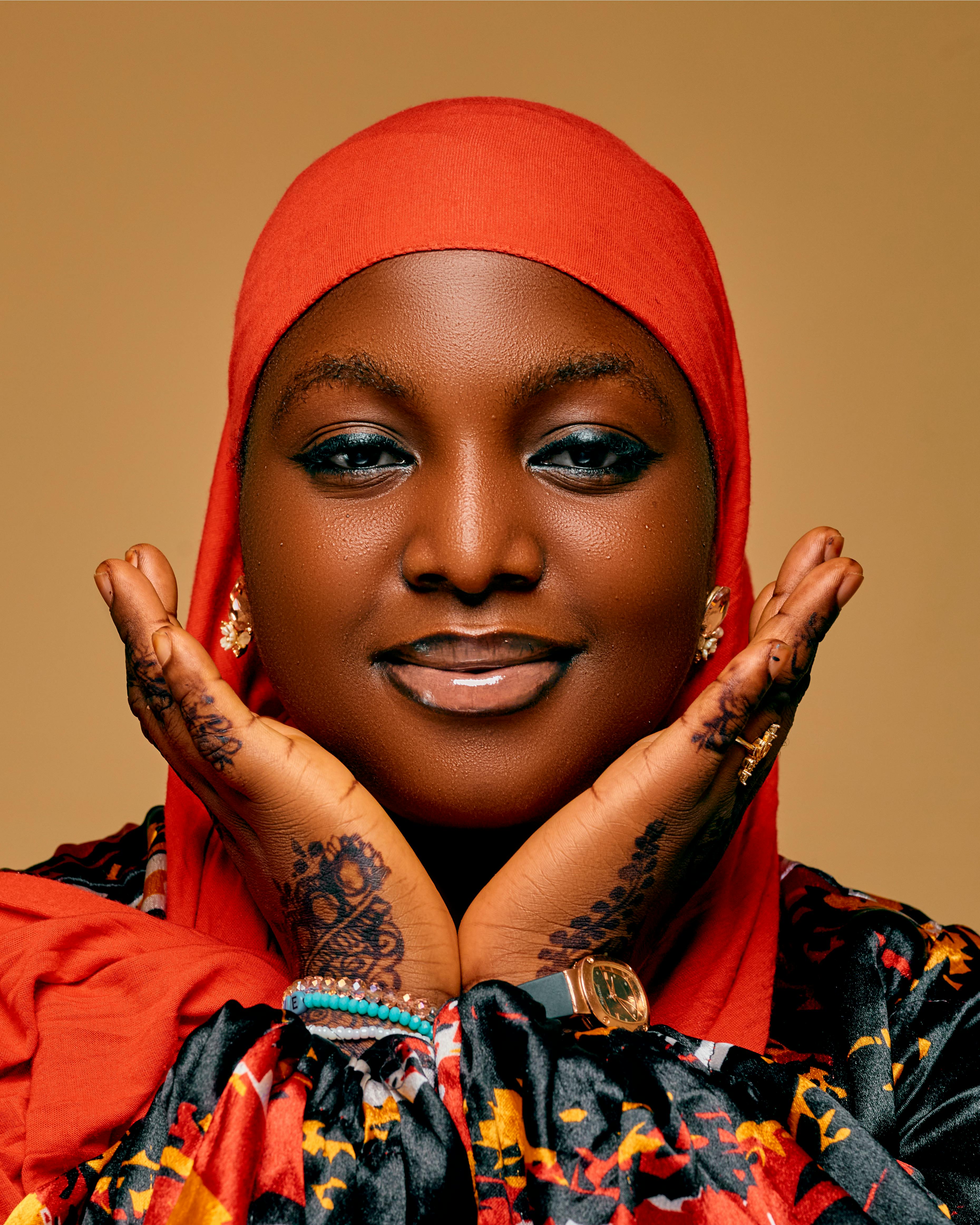 Beautiful portrait of a woman in red hijab with intricate henna designs on hands.
